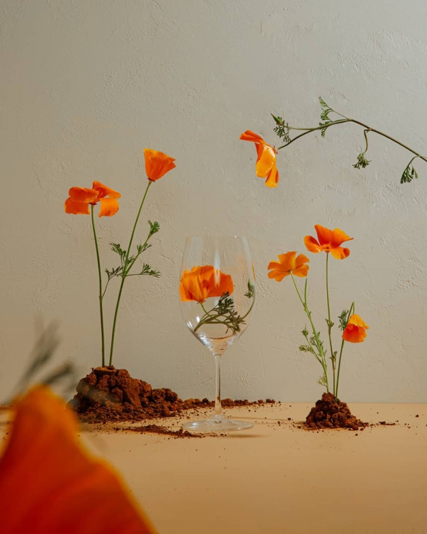 An empty wine glass on a table surrounded by flowers